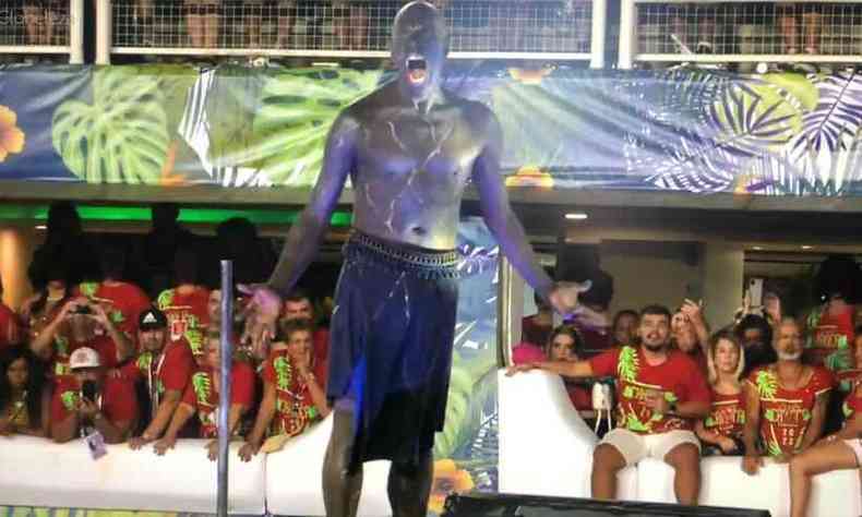 bailarino Rui Moreira, sem camisa, desfila na escola de samba Beija-Flor. Ao fundo, v-se a plateia nos camarotes da Marqus de Sapuca