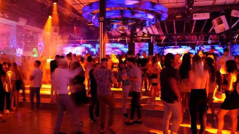 Jovens danando em um clube onde h imagens coloridas em teles nas paredes