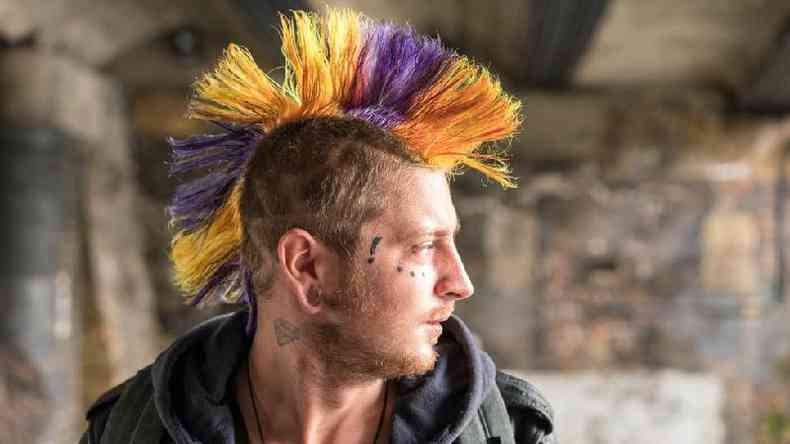 Homem com rosto tatuado e cabelo punk colorido