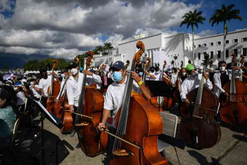 msicos em fila tocam violoncelos a cu aberto em Caracas