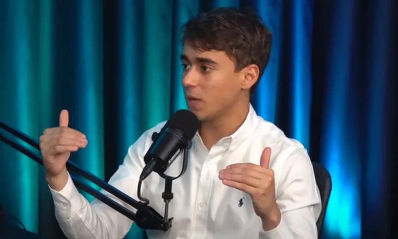 Nikolas Ferreira afirmou que negar o holocausto e permitir a existência de um partido nazista são atitudes enquadradas na 'liberdade de expressão'(foto: Reprodução) Nikolas Ferreira usando camisa social branca falando em um microfone durante gravação de podcast em um fundo azul escuro