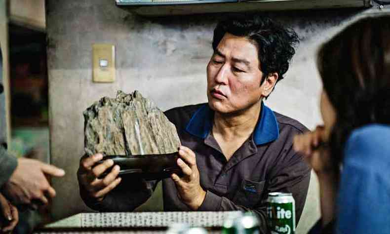O chefe do cl Kim (Song Kang-ho) inspeciona a %u201Cpedra da riqueza%u201D em Parasita(foto: Pandora Filmes/Divulgao)