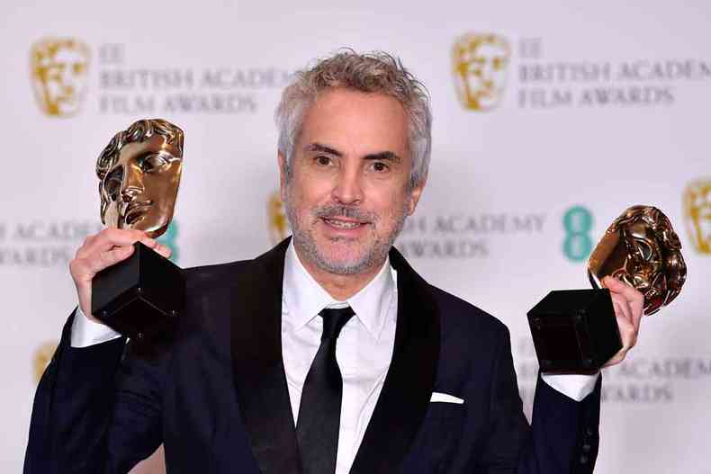 O mexicano Alfonso Cuarn exibe as estatuetas de melhor filme e diretor, em Londres(foto: Ben Stall/AFP)
