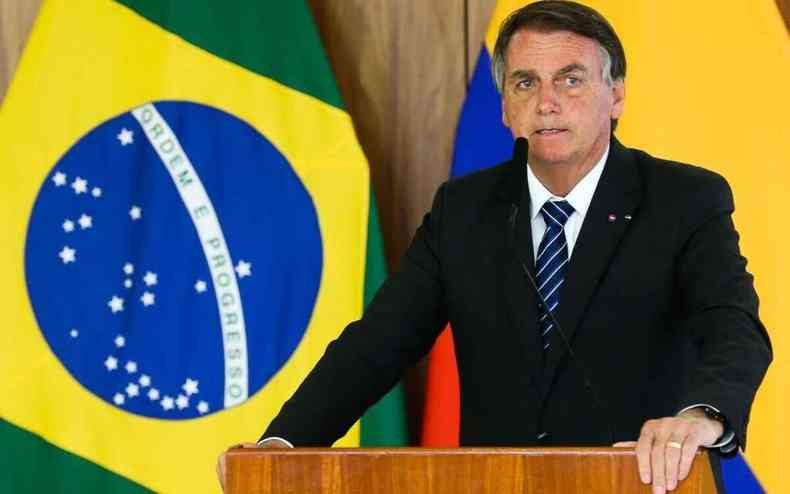 Presidente Bolsonaro, com bandeira do Brasil ao fundo
