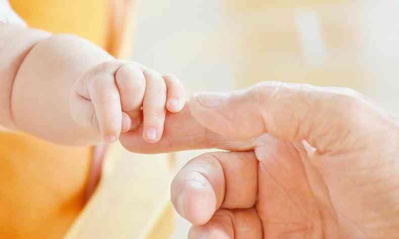 Adulto segura o dedo de beb