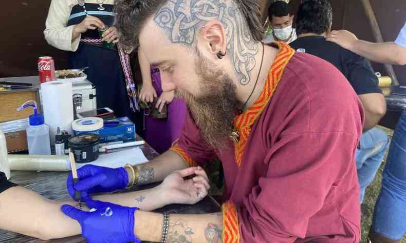 Hafr tatuando a mão na técnica handpoke