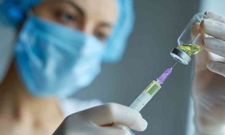 Enfermeira retirando lquido de ampola com a seringa