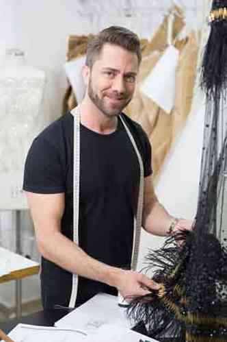 Lucas Anderi no seu ateliê de costura, com fita métrica em volta do pescoço