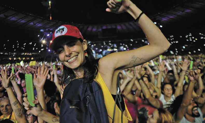 Isabela Oliveira sorri e ergue o brao, onde est tatuado trenzinho da capa do disco de Milton Nascimento, durante show do cantor no Mineiro