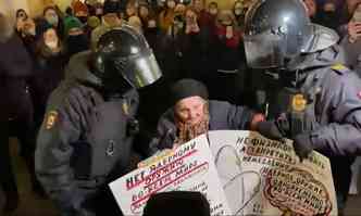 Elena Osipova segurando seus cartazes enquanto  levada presa por dois policiais russos