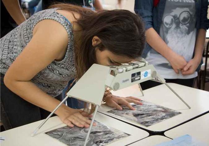 Aluna experimenta a inspeção de fotografias de relevo em espaço de geografia(foto: Daniel Caminhas/UFMG) Aluna experimenta a inspeção de fotografias de relevo em espaço de geografia(foto: Daniel Caminhas/UFMG)