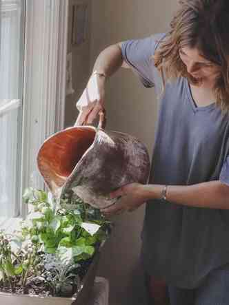 mulher regando horta na cozinha