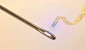 O invento  mostrado ao lado de uma agulha: a espessura do dispositivo  20 vezes menor que a de um fio de cabelo(foto: UNIVERSITY OF ILLINOIS/URBANA CHAMPAIGN/WASHINGTON UNIVERSITY-ST. LOUIS/DIVULGAO)