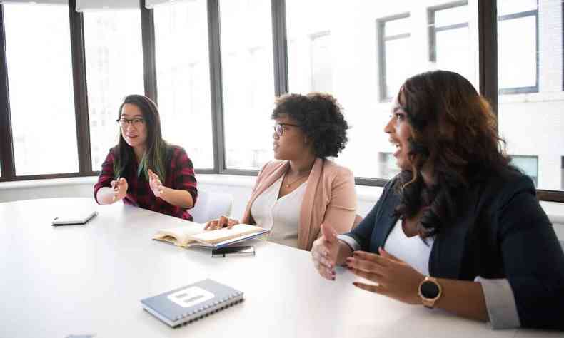 Trs mulheres conversando em uma mesa de reunies