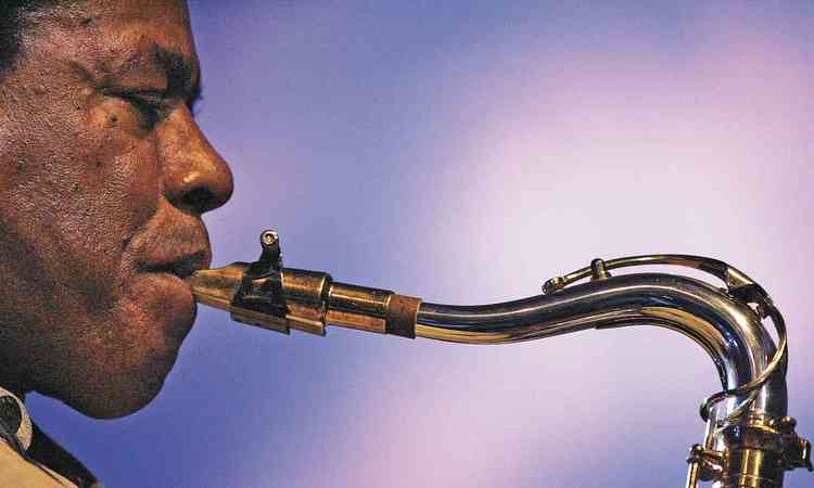 De olhos fechados, Wayne Shorter toca saxofone no palco
