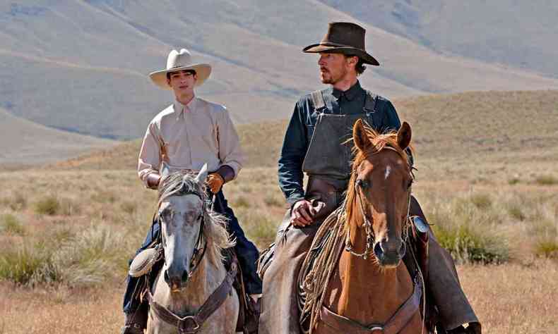 Os atores Kodi Smit-McPhee e Benedict Cumberbatch montados a cavalo em cena do longa ataque dos cães