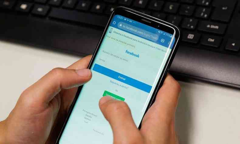 pessoa acessa o Facebook pelo smartphone