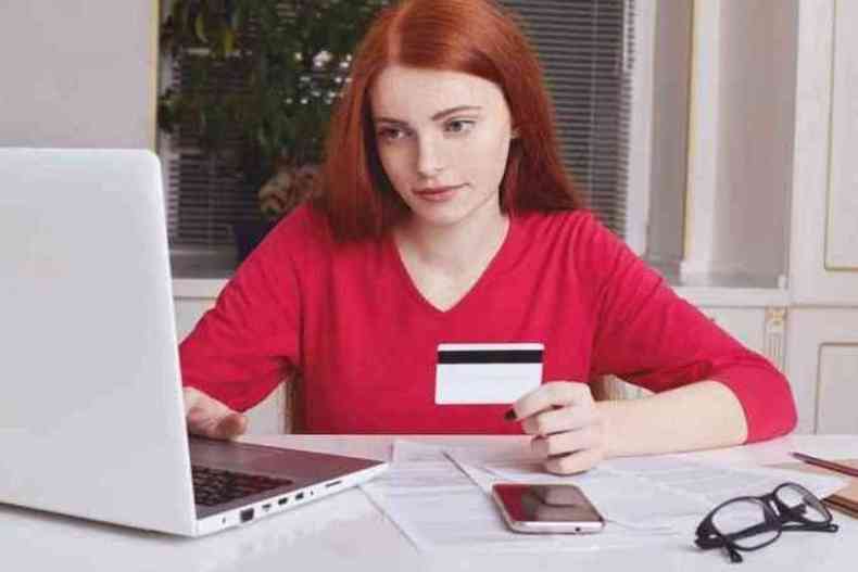 Menina segura o carto para fazer compra pela internet