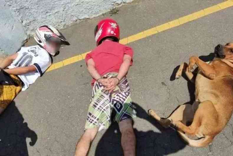 Cachorro deitado ao lado de dois homens com capacete em uma abordagem policial