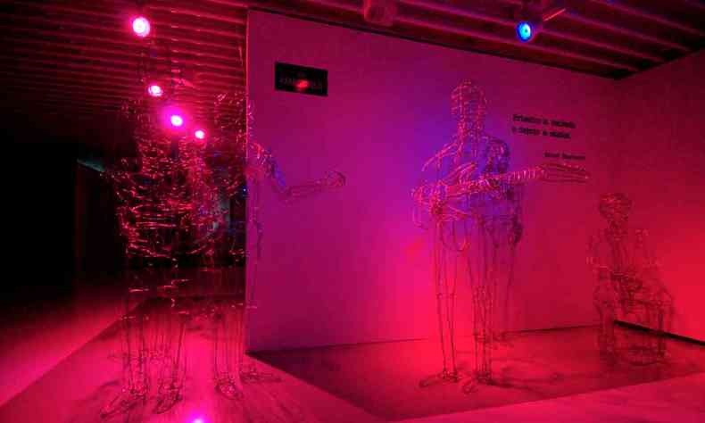 objetos de metal simulando silhueta humana com instrumento em ambiente avermelhado na galeria do Minas Tnis Clube