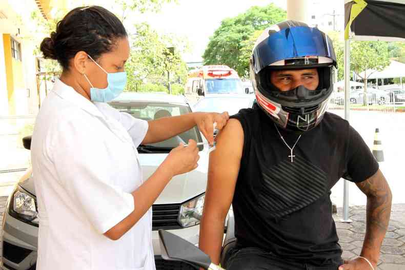 Motociclista recebendo a vacina contra a COVID no brao direito