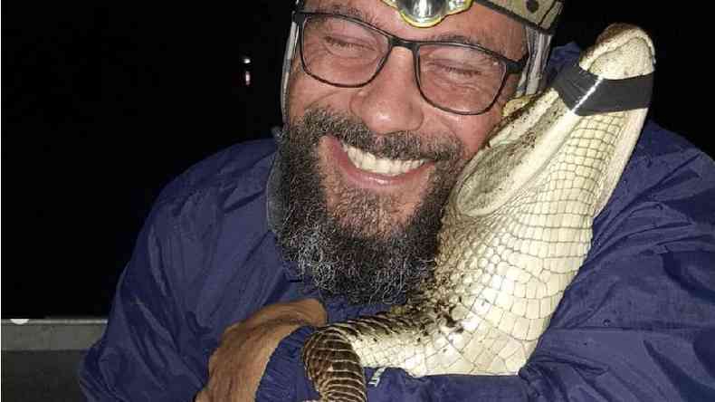 O biólogo Ricardo Freitas sorri enquanto segura um pequeno jacaré