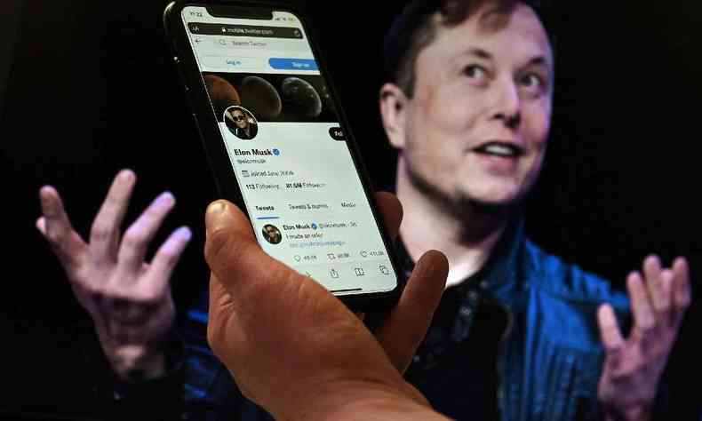 Nesta foto de arquivo tirada em 14 de abril de 2022 Nesta ilustrao fotogrfica, uma tela de telefone exibe a conta do Twitter de Elon Musk com uma foto dele mostrada ao fundo, em 14 de abril de 2022, em Washington, DC