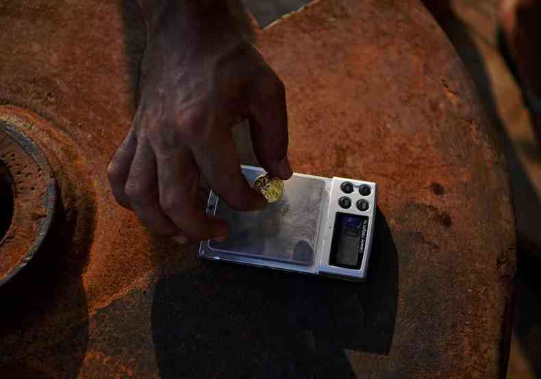 Garimpeiro ilegal pesa pepita de ouro em balano dentro de barco na Amaznia