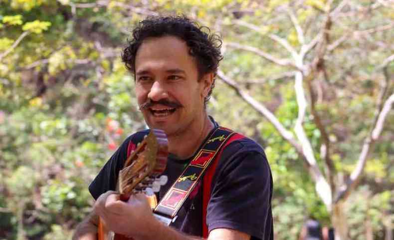 cantor e compositor Edu Pio segura violo entre rvores