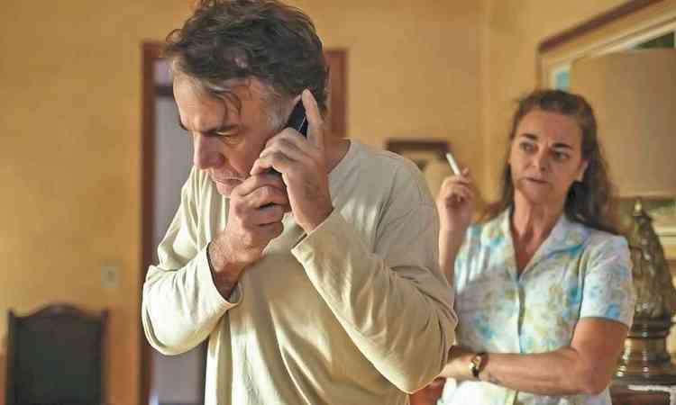 Ator Eduardo Moreira fala ao telefone e atrs dele est a atriz Ins Peixoto, em cena do filme O lodo

