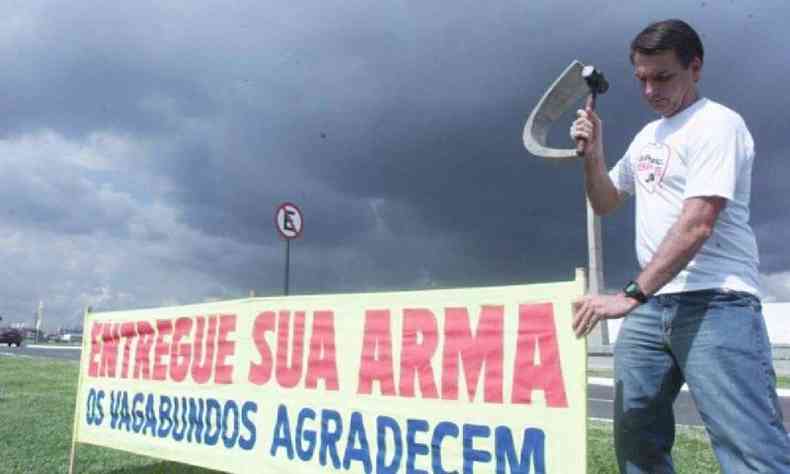Jair Bolsonaro com faixa escrito 'Entregue sua arma. Os vagabundos agradecem'