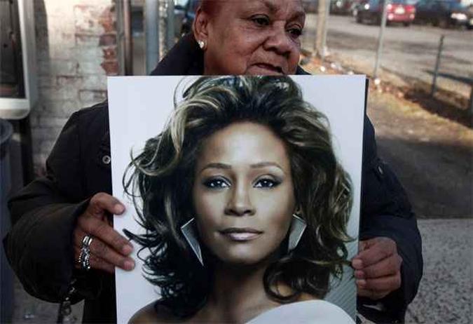 Maria Guerrido mostra um poster de Whitney na frente da igreja onde acontecer o funeral(foto: REUTERS/Carlo Allegri)