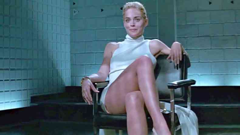 Sharon Stone, de vestido branco, cruza as pernas no filme Instinto selvagem
