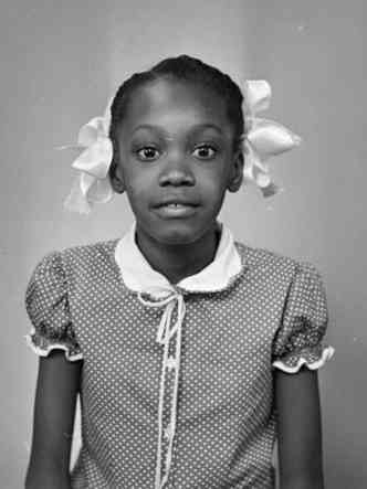 Menina negra com lao de fita olha para a cmera em foto de Limercy Forlin