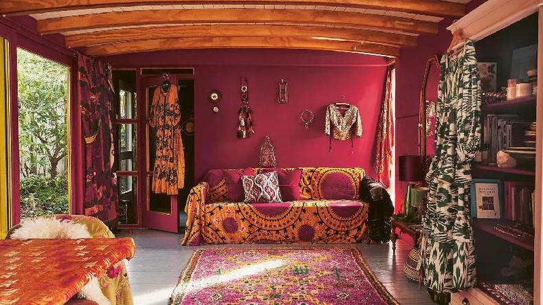 Fotografia colorida mostra uma sala com paredes rosa e roupas penduradas nas paredes e portas