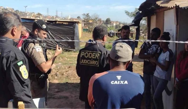 Oficial de justia conversando com moradores, acompanhado da Polcia Militar