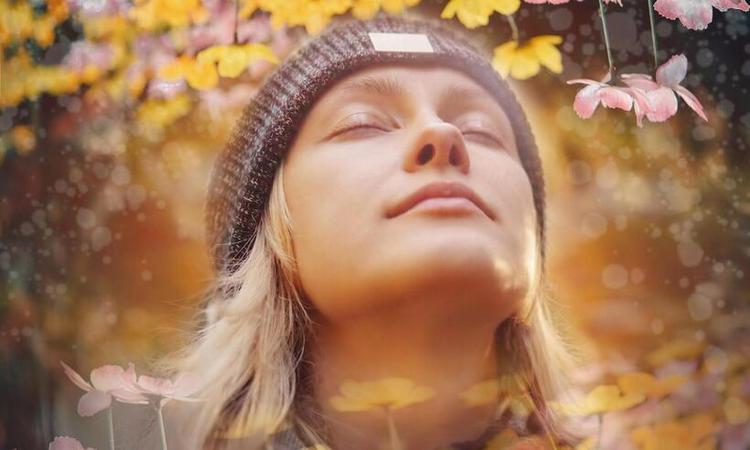 mulher de olhos fechados respira em meio a um jardim com vrias flores