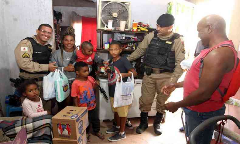 Imagem mostra Célia e os filhos recebendo doações de militares e vizinhos
