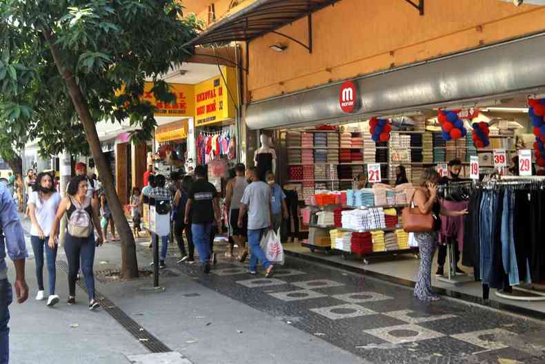 pessoas andando na rua em frente a uma loja