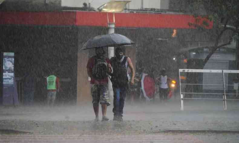 Dois pedestres dividem guarda-chuva em tarde de forte chuva em BH