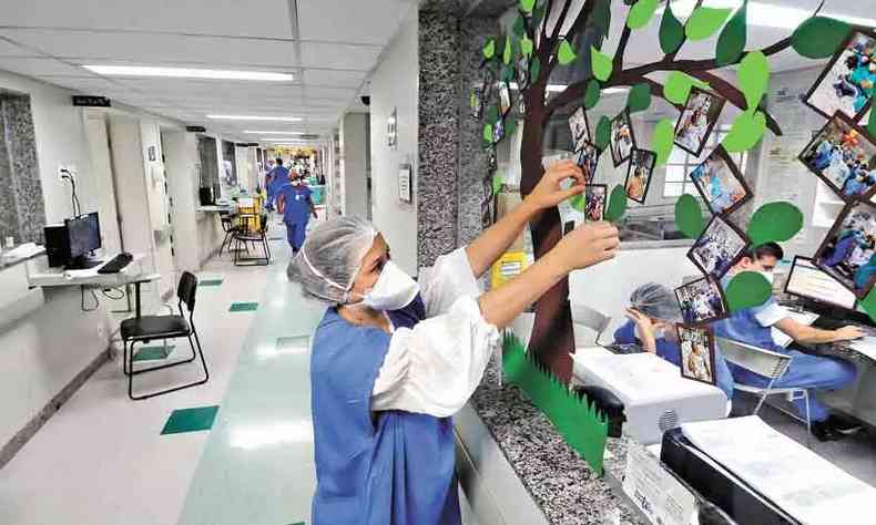 Enfermeira pendura fotos de pacientes em painel de hospital