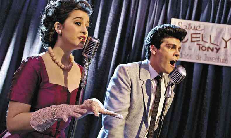 Vestidos com roupas dos anos 50, os atores Marianna Alexandre e Murilo Armacollo cantam em estdio de rdio no filme 'um broto legal'