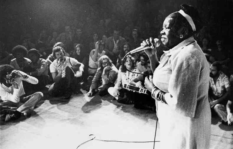 Clementina de Jesus canta e  ouvida por jovens sentados no cho