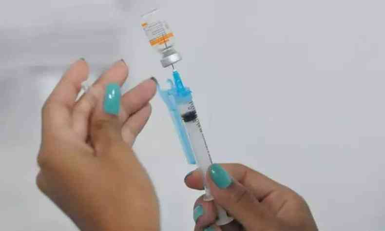 Mos de uma mulher enche seringa com contedo de um frasco de vacina
