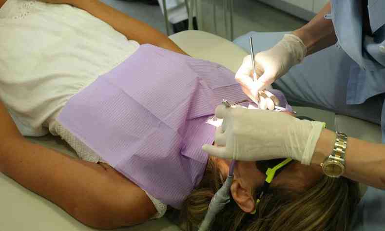 dentista mexendo no dente de paciente 