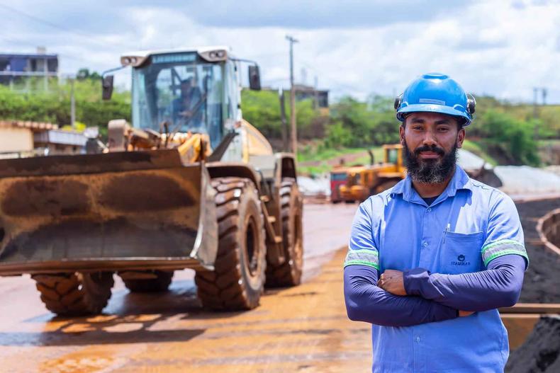 Colaborador da Itaminas no primeiro plano e um trator no segundo plano