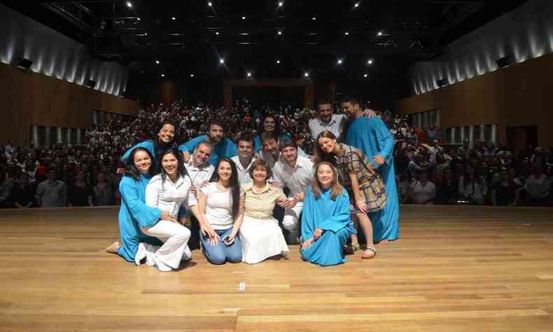 Elenco da pea 'Violetas na janela' posa no palco, tendo ao fundo a plateia. Vestindo saia branca e blusa amarela, a atriz Ana Rosa est no centro da trupe