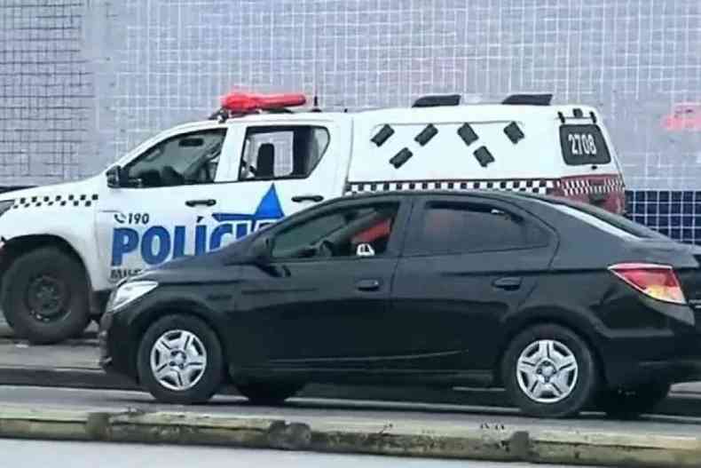 Na foto est um carro de polcia parado ao lado de um carro preto 