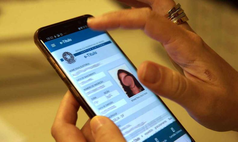 Pessoa mexendo num celular, no e-ttulo, verso digital do ttulo de eleitor