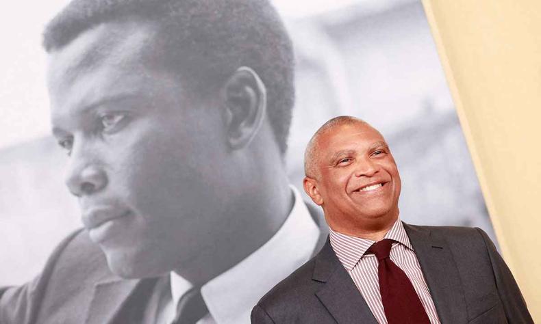Diretor Reginald Hudlin sorri. Atrs dele, na parede, est uma foto do ator Sidney Poitier